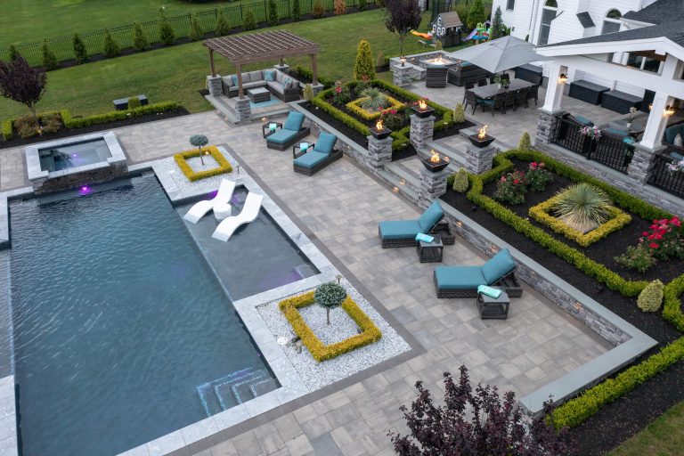 A modern backyard with a pool, lounge chairs, fire pits, pergola, and landscaped garden beds.