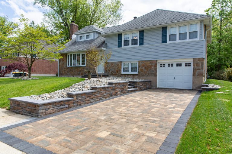 Two-story suburban house with stone and siding exterior, landscaped yard, and paved driveway.