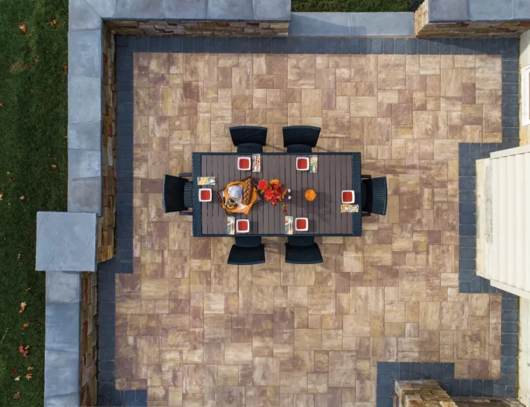 Aerial view of a patio with a rectangular dining table set for six, surrounded by stone walls and tile flooring.