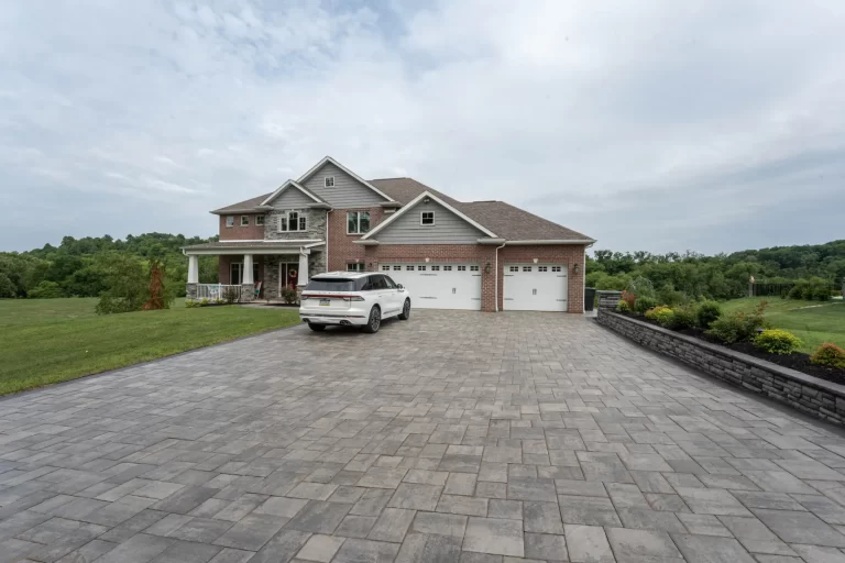 Large brick house with a three-car garage, a white SUV parked in the driveway, and a landscaped yard.