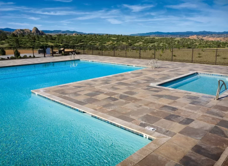 Outdoor swimming pool with a hot tub, tile deck, and scenic mountain landscape in the background.