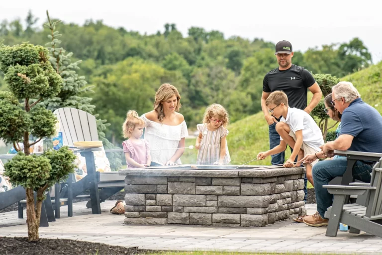 A family gathers around a fire pit outdoors, roasting marshmallows and enjoying time together.